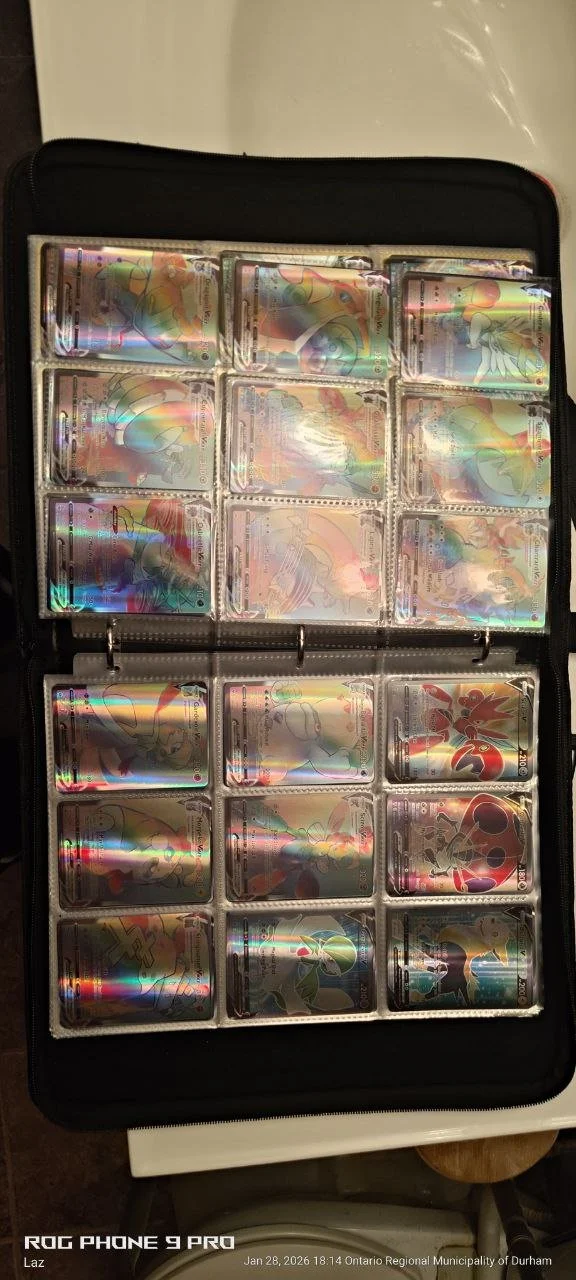Collection of holographic Pokémon cards in a black binder with plastic sleeves.