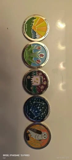 A vertical lineup of five circular cans with colorful designs, each featuring different artistic patterns and characters, placed on a light surface.