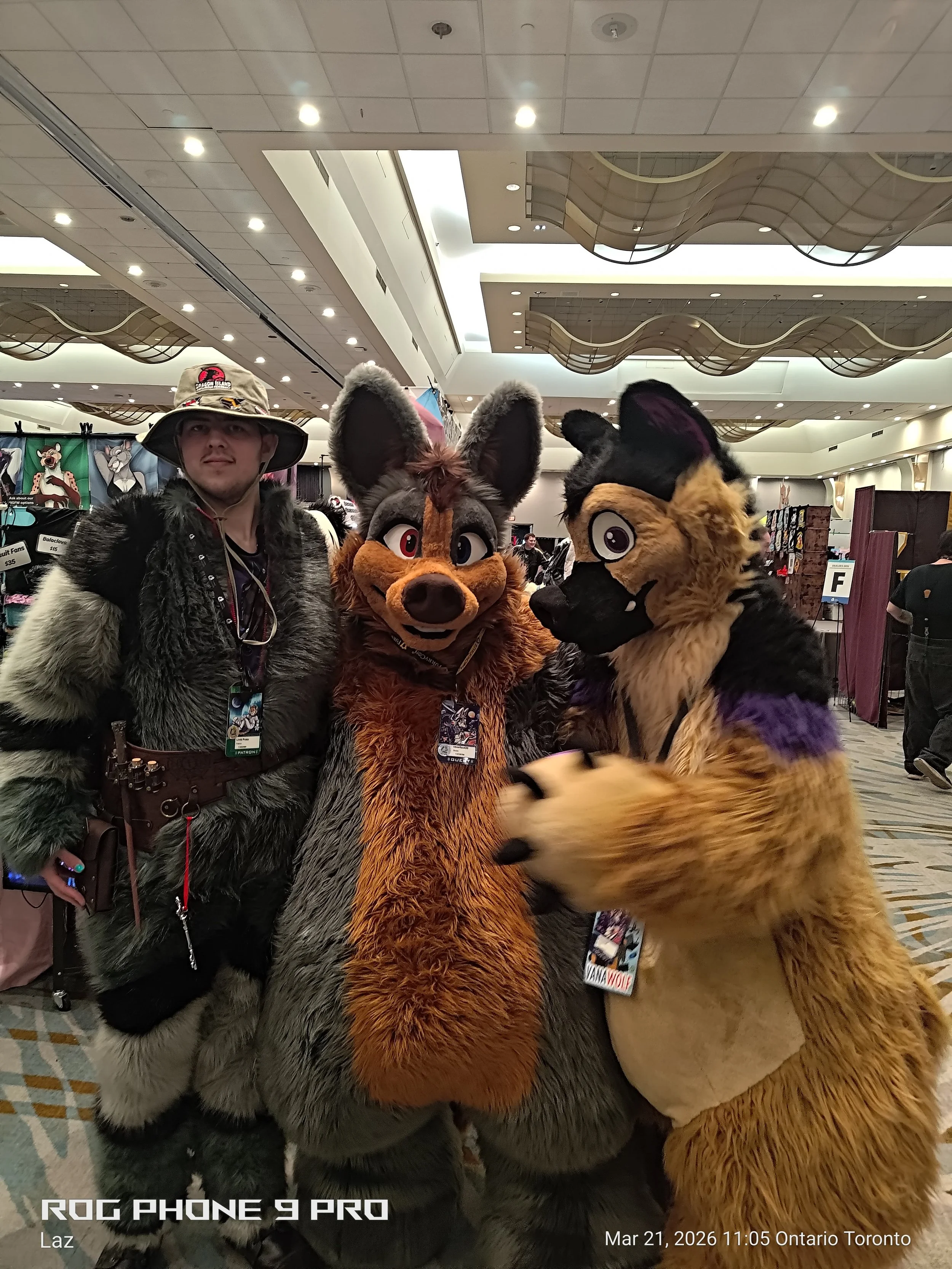 Person in a furry costume standing between two other people in animal costumes at an indoor convention