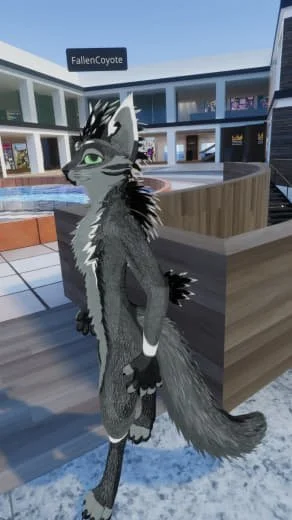 A furry anthropomorphic wolf character with grey and black fur and green eyes standing in a modern outdoor area with a building and a sign that says 'FallenCoyote'.