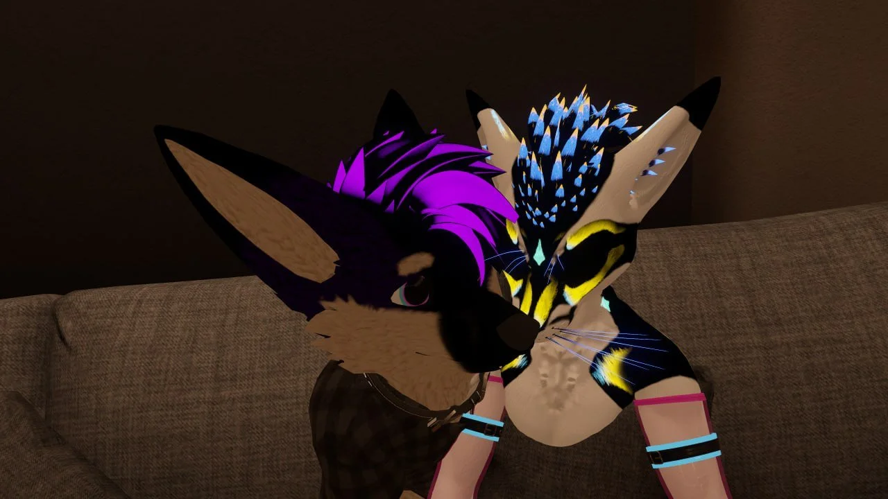 Two anthropomorphic characters with feline features sitting close together on a couch, one has purple hair and the other has blue and yellow striped fur and bright colorful feathers on its head.