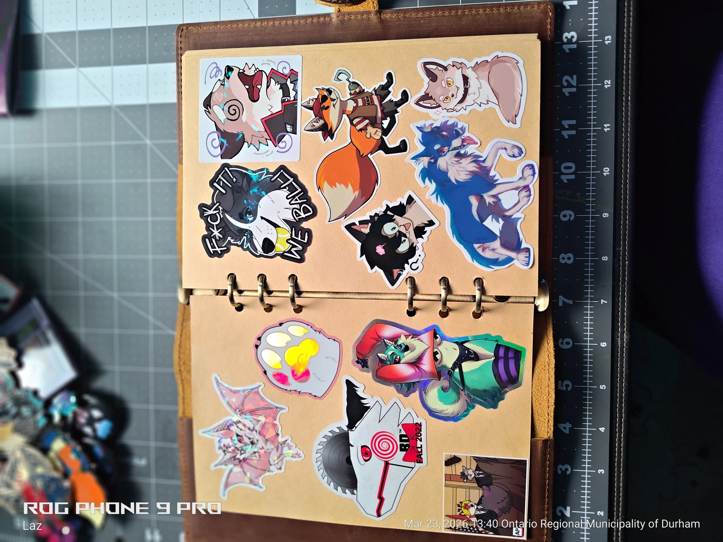 Collection of colorful stickers with various designs including an angry wolf, a happy wolf, a fox, a bat, a dog with sad eyes, a wolf with sunglasses, and other fantasy and animal characters, displayed on a tan notebook with a ruler along the right s