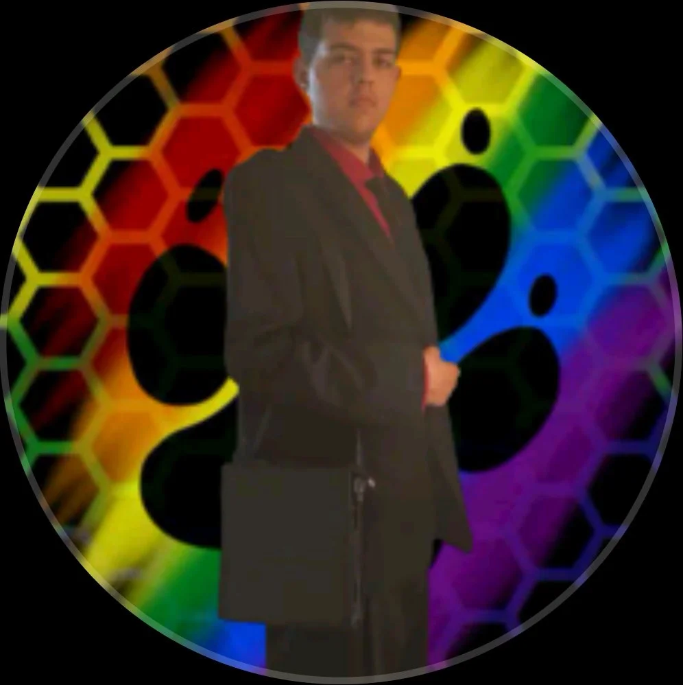 A young man in a black graduation gown standing in front of a colorful rainbow background with honeycomb and molecule patterns.