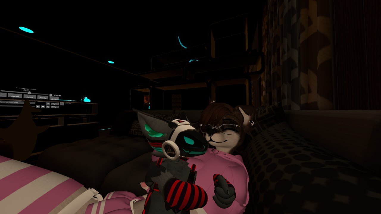 Animated image of a humanoid cat character wearing sunglasses and a pink hoodie, sitting on a couch at night, holding a gaming controller shaped like a robotic dog.