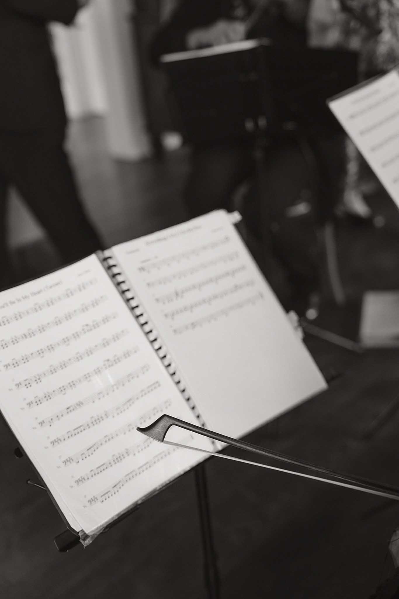 A music stand holding sheet music with musical notes, a metal wrench, and a music stand with a sheet of music attached.