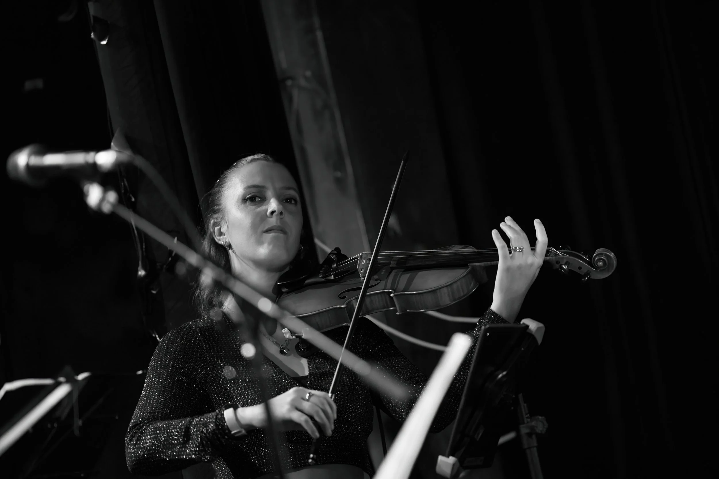A woman playing a violin on stage during a performance, black and white photo.