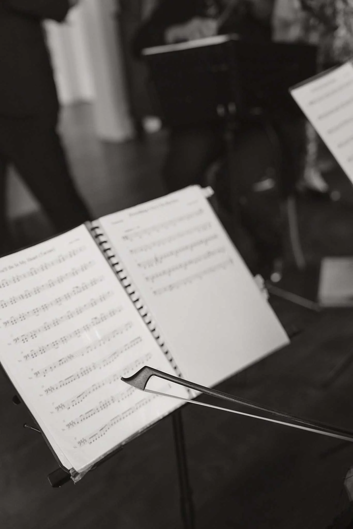A music stand holding sheet music, with a baton in the foreground, on a black chair.
