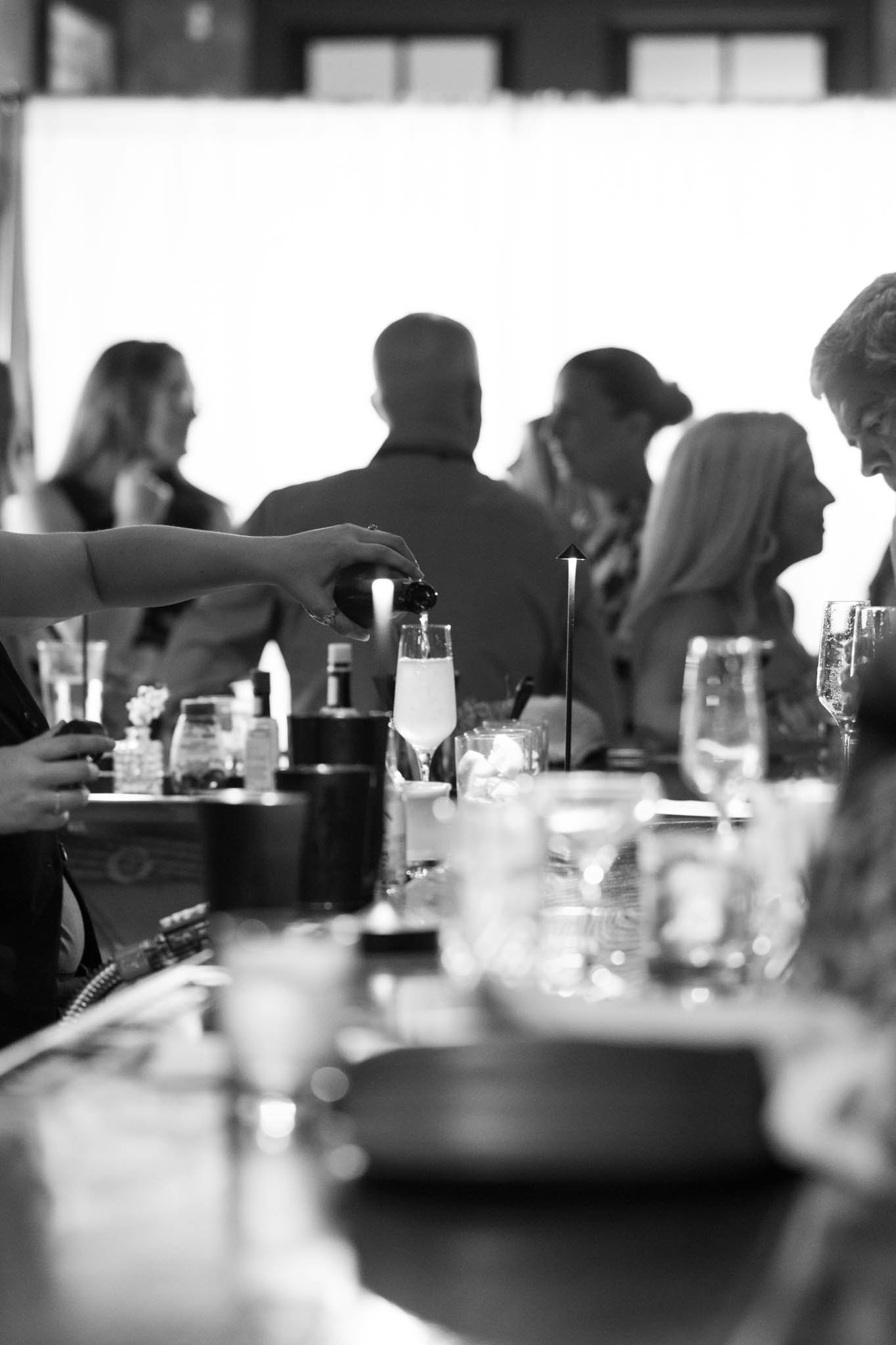 Silhouette of people gathered at a table with drinks, in a dimly lit setting, possibly a bar or restaurant.