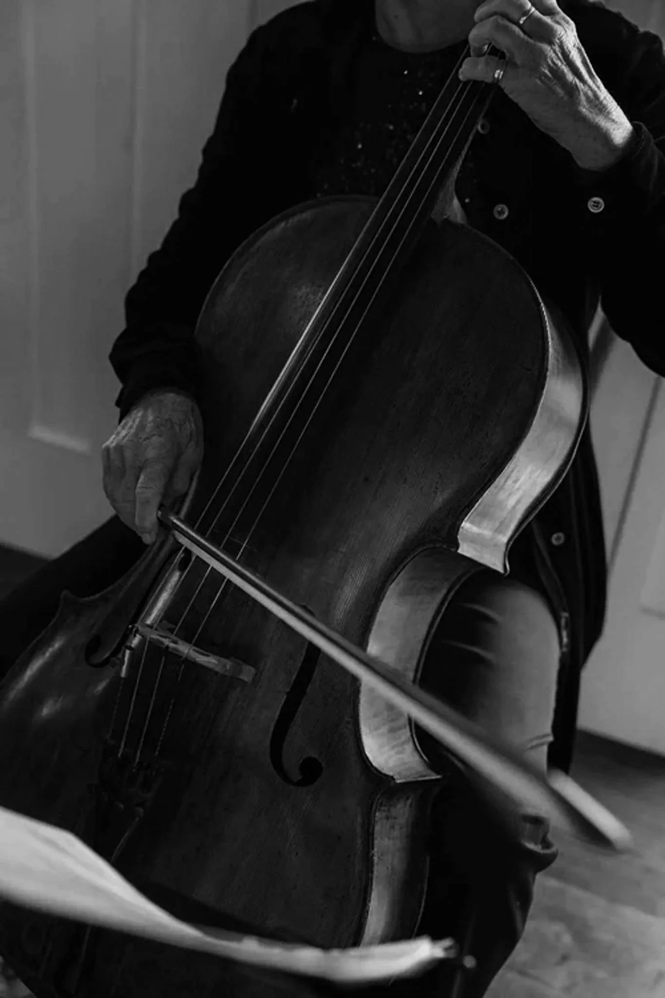 A person playing a double bass, captured in black and white, focusing on their hands and the instrument.