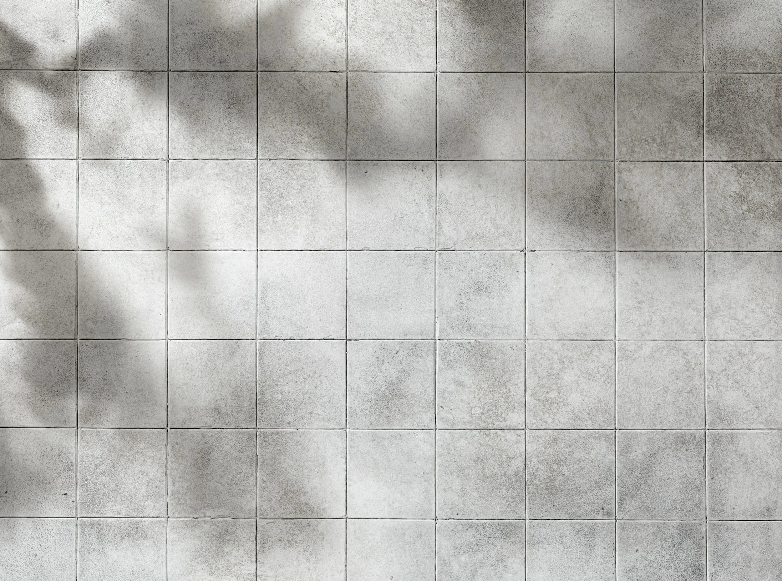 A tiled floor with light and dark patches, possibly shadows or stained areas.