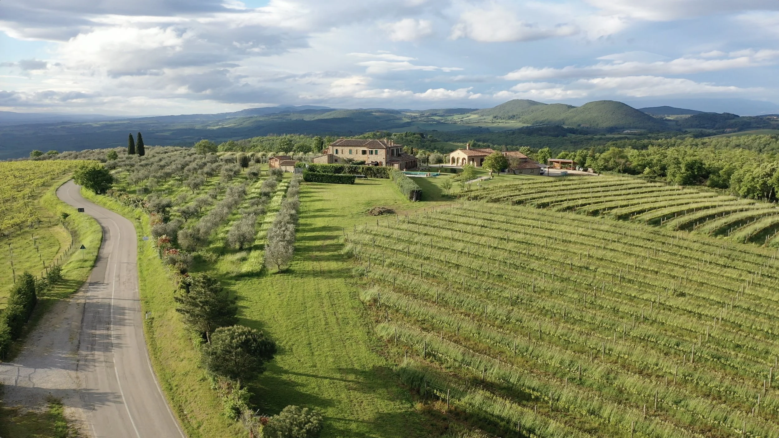 Arial view of a Tuscan property surrounded by vineyards and rolling green hills