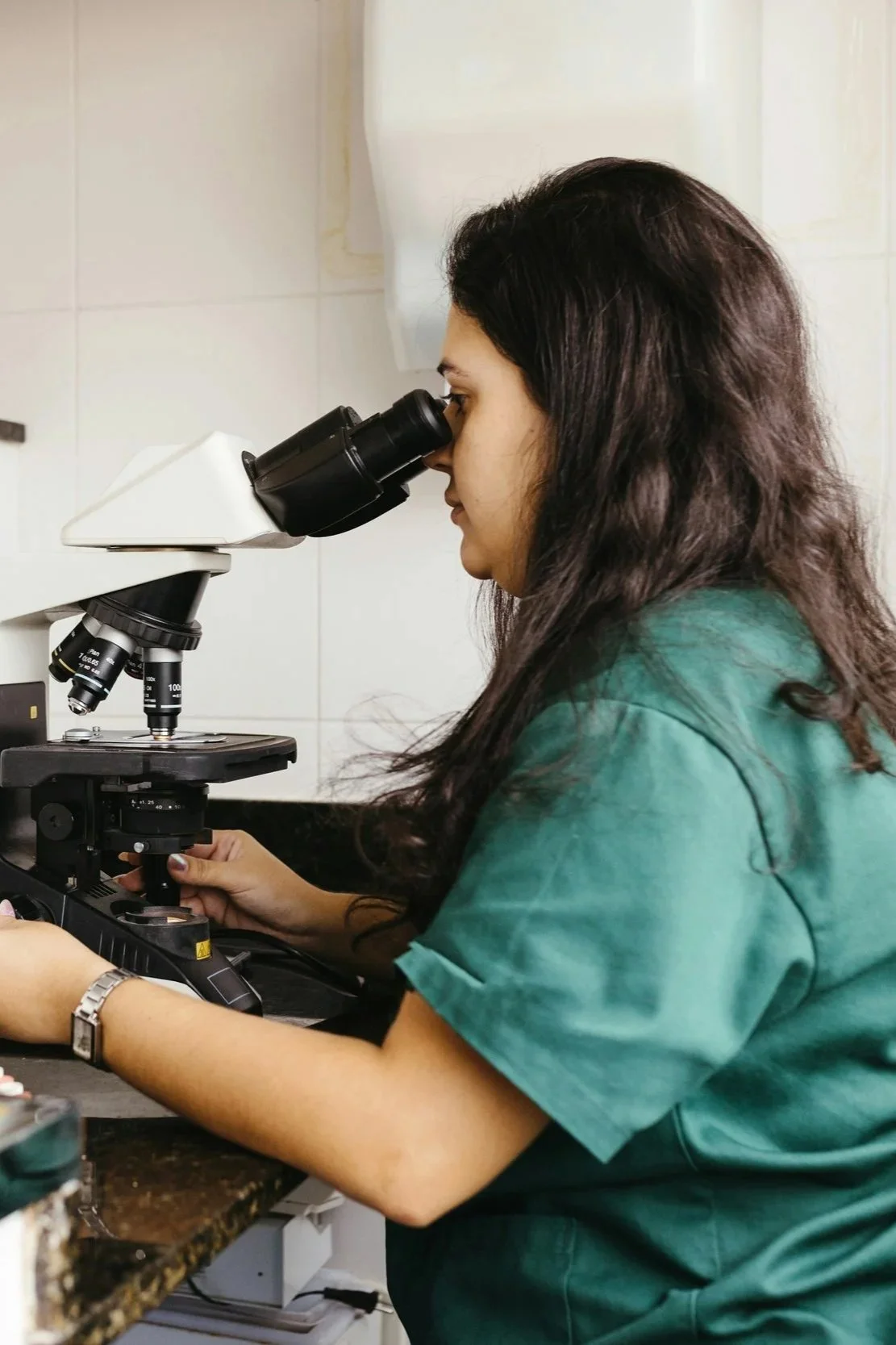 A woman looking through a microscope in a laboratory setting.