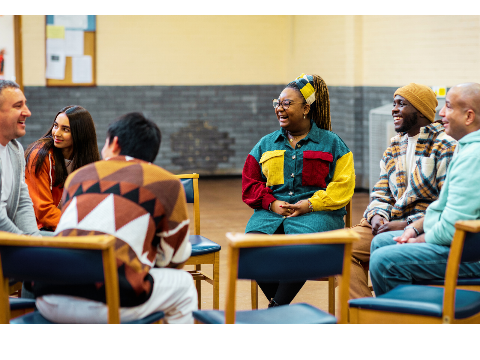 A diverse group of adults gathered in a circle for a community discussion.
