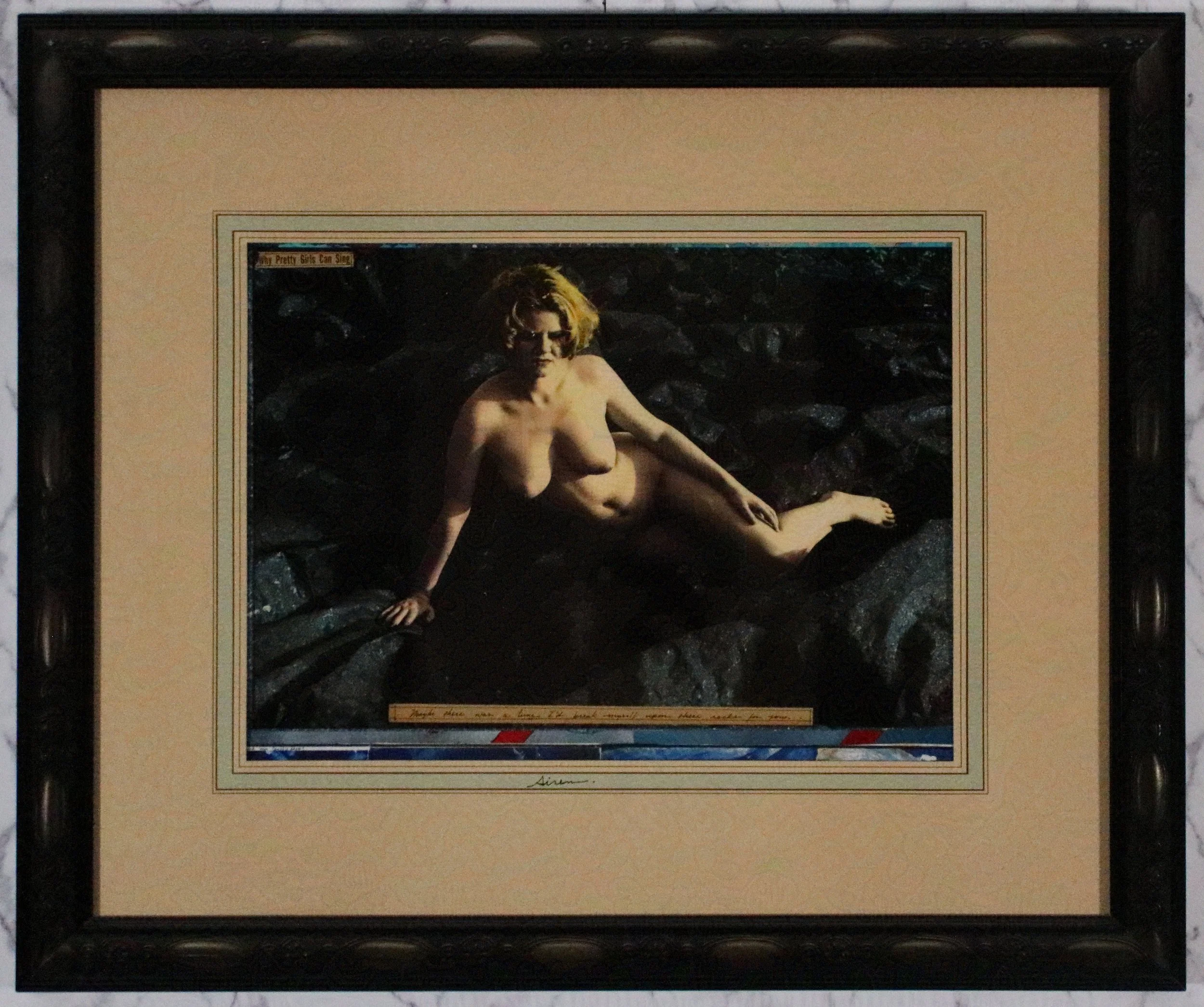 A framed painting of a nude woman reclining on a dark rocky surface, with her arms and legs positioned naturally. The painting has a signature at the bottom and a small caption in the top left corner reading "My Pretty Girls Can Sing."