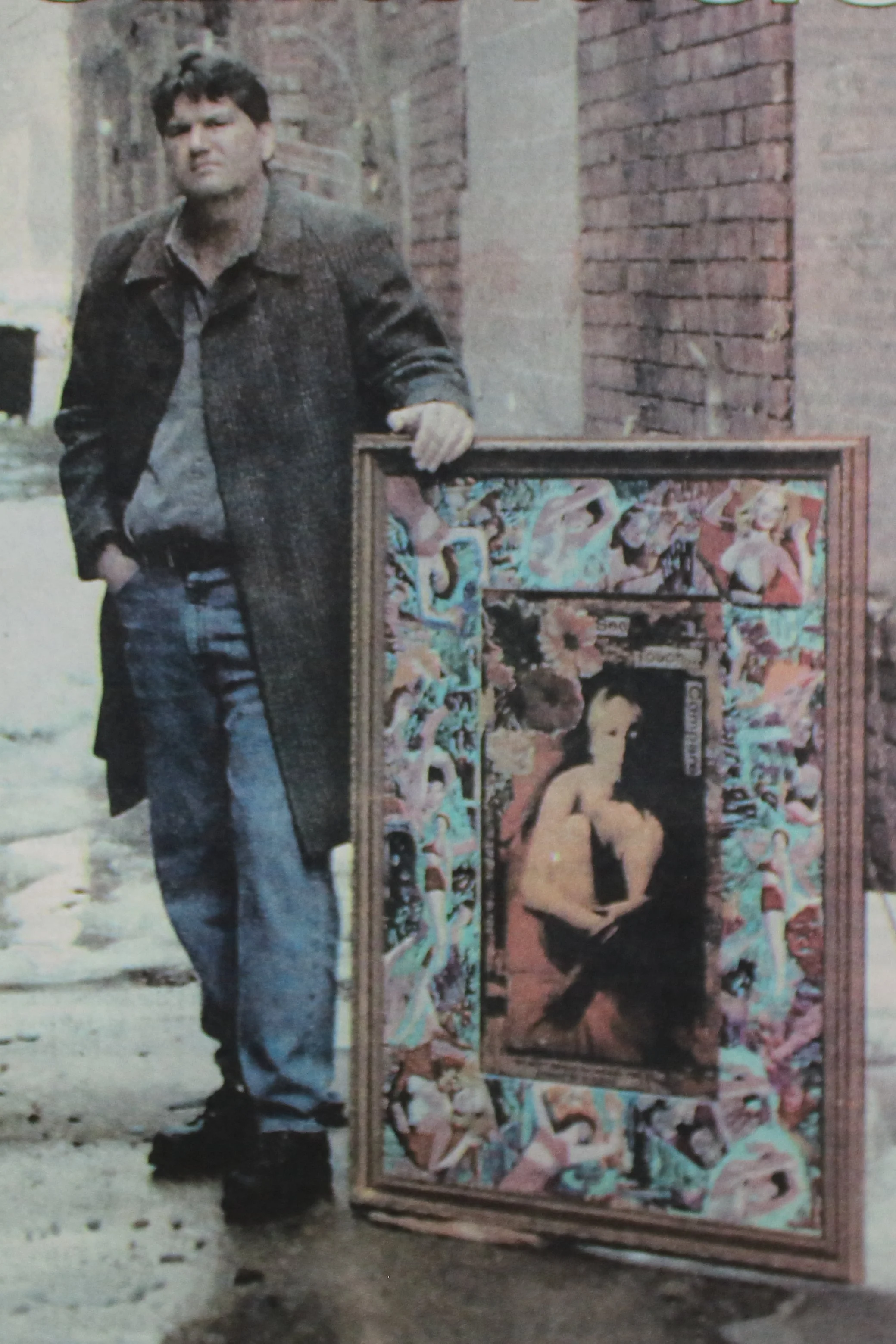 A man standing next to a colorful painting proyecting a woman with a revealing outfit.