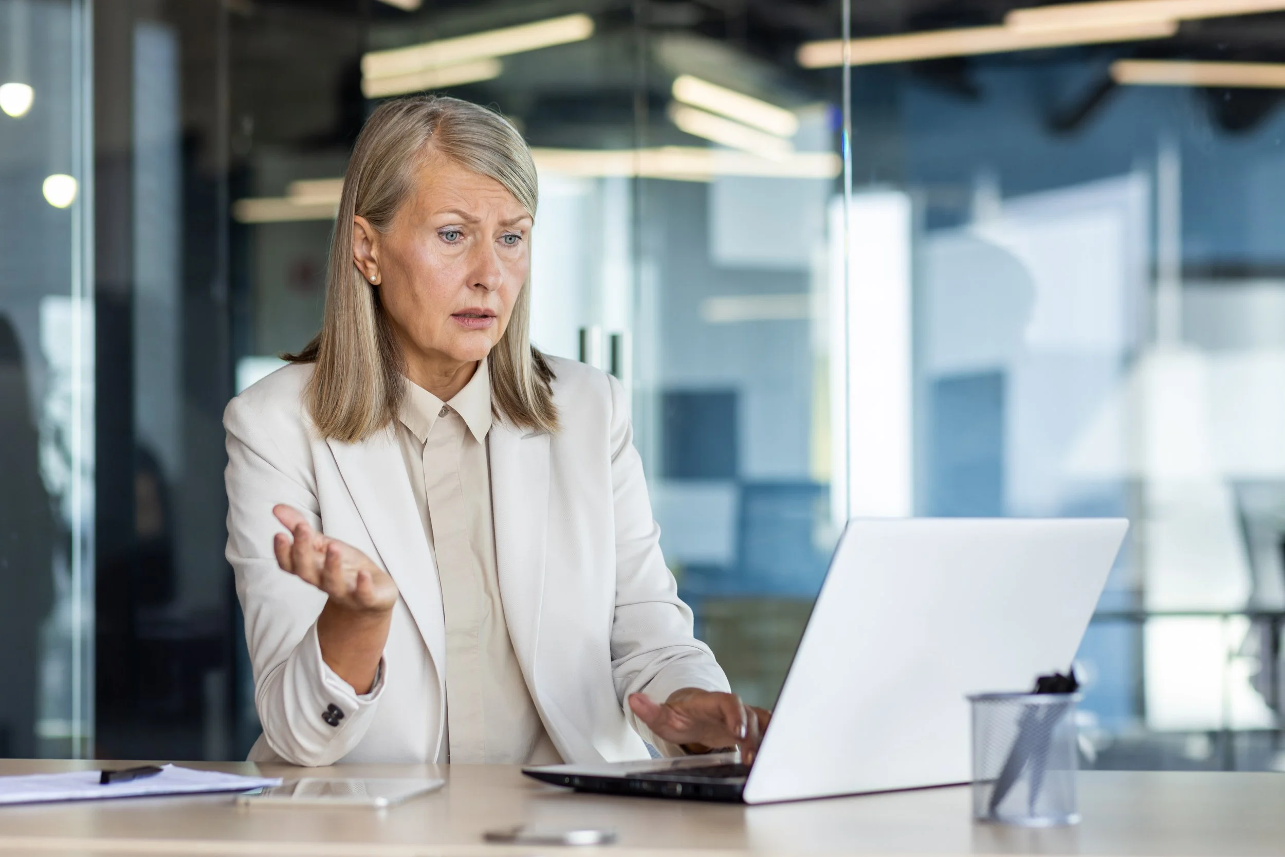 Woman in an office looking concerned while reviewing finances on her laptop — symbolizing retirement spending stress