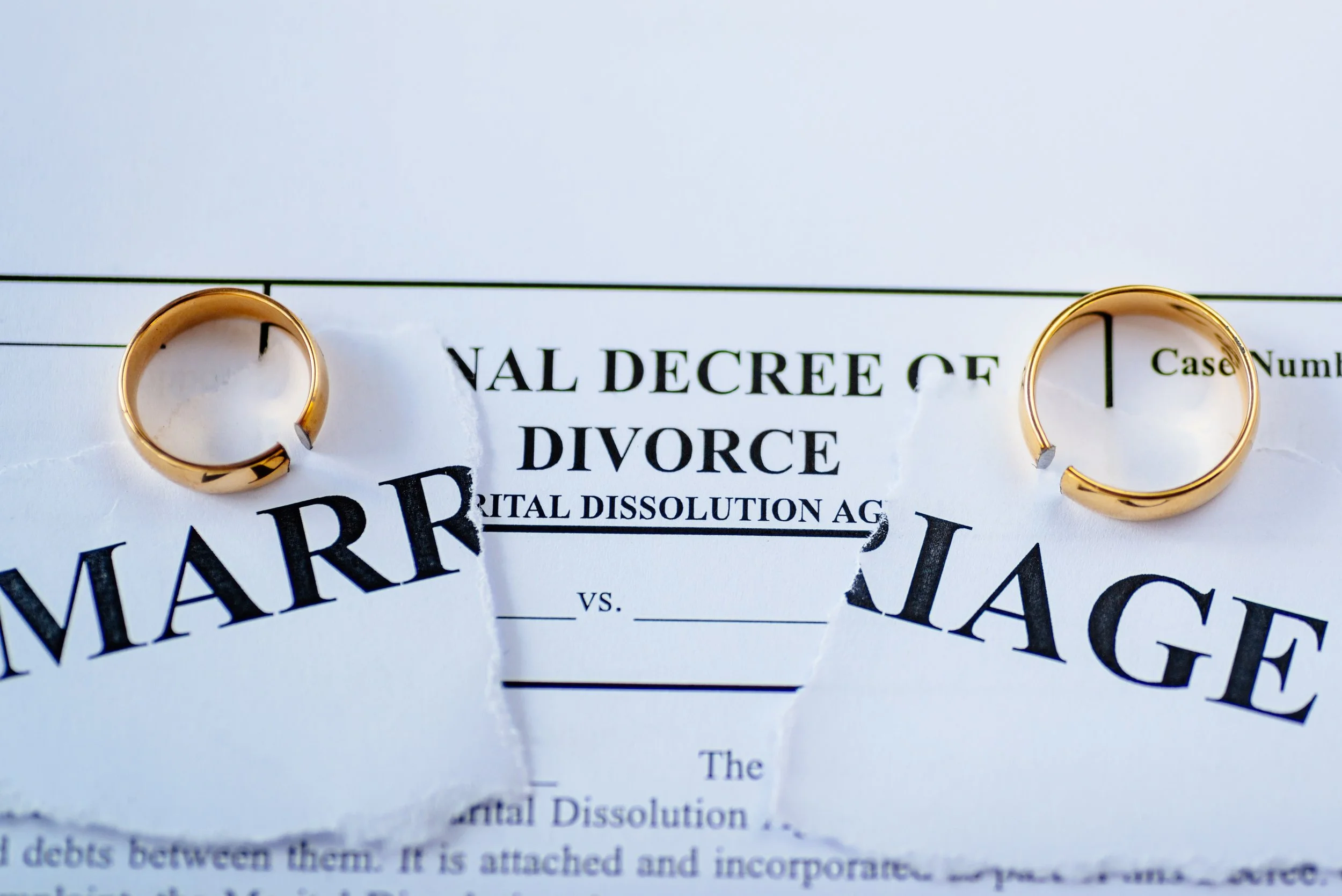 Torn marriage certificate and divorce decree with two wedding rings, representing spousal and divorced spouse Social Security benefits