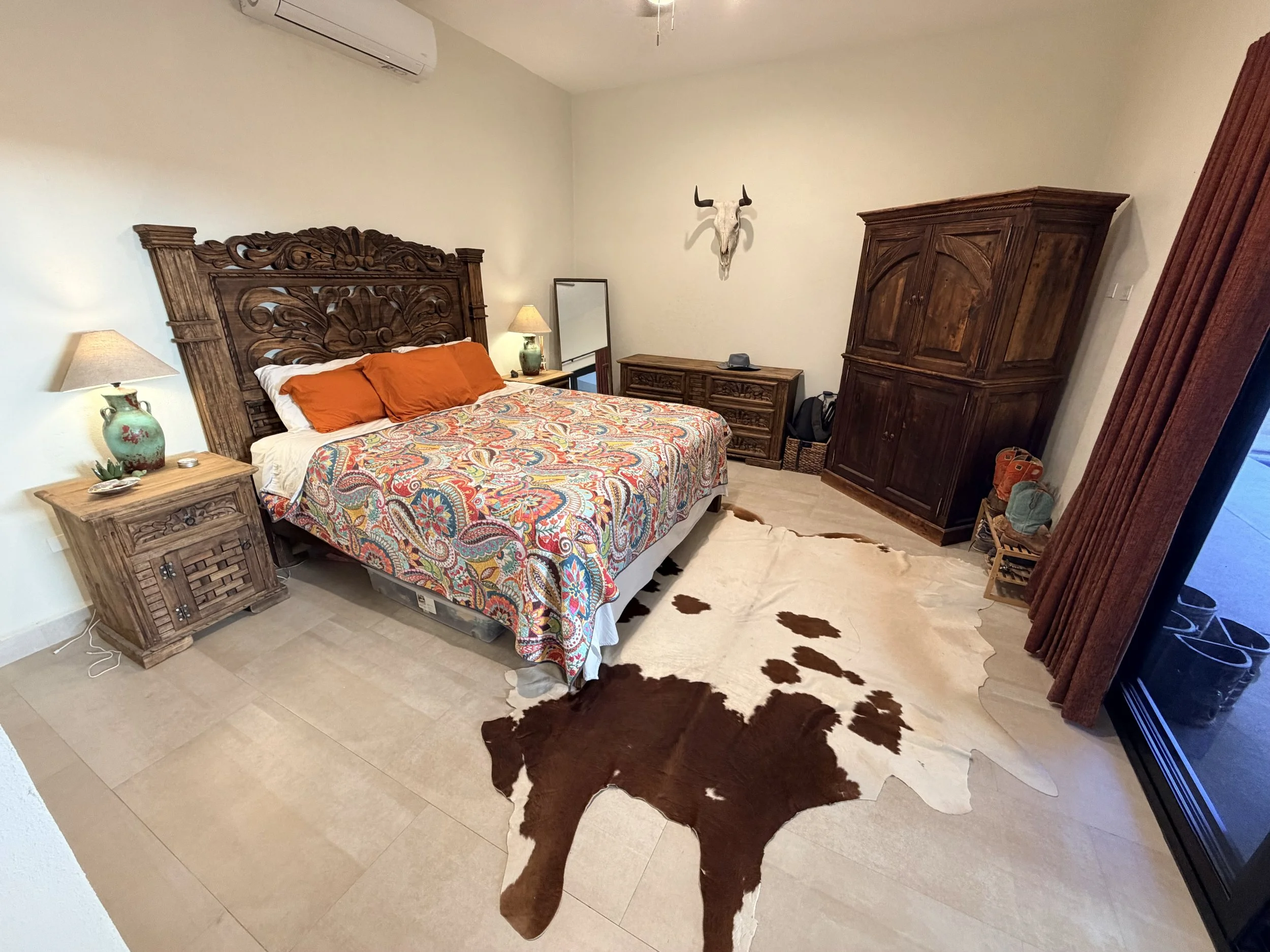 A bedroom with wooden furniture, a cowhide rug, and a cow skull decoration on the wall.