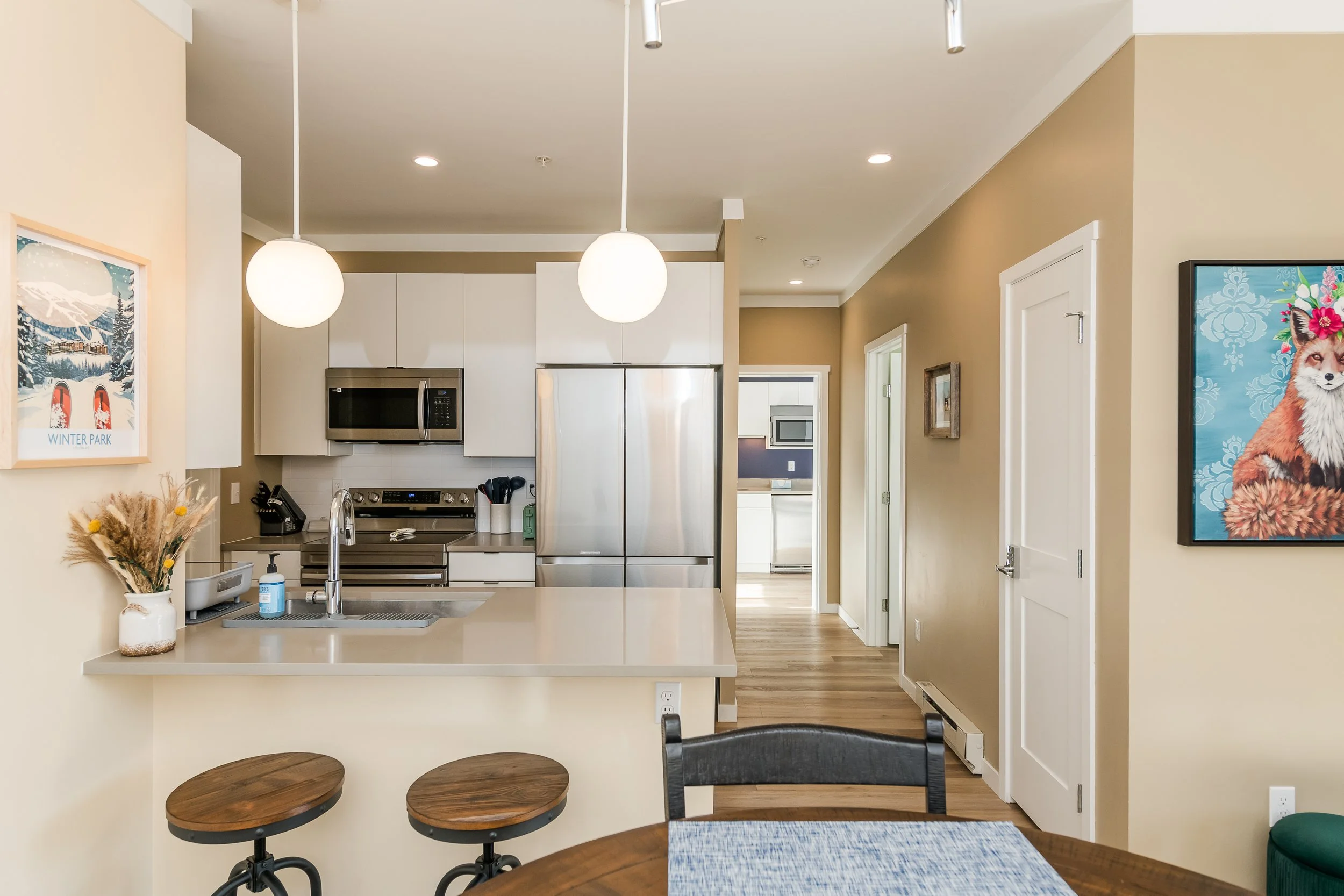 Bright modern kitchen with white cabinets, stainless steel appliances, and pendant lights