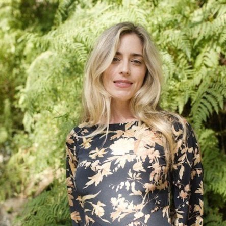 blonde haired female infront of green leaves