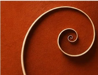 Close-up of a decorative metal or wooden swirl against an orange background.
