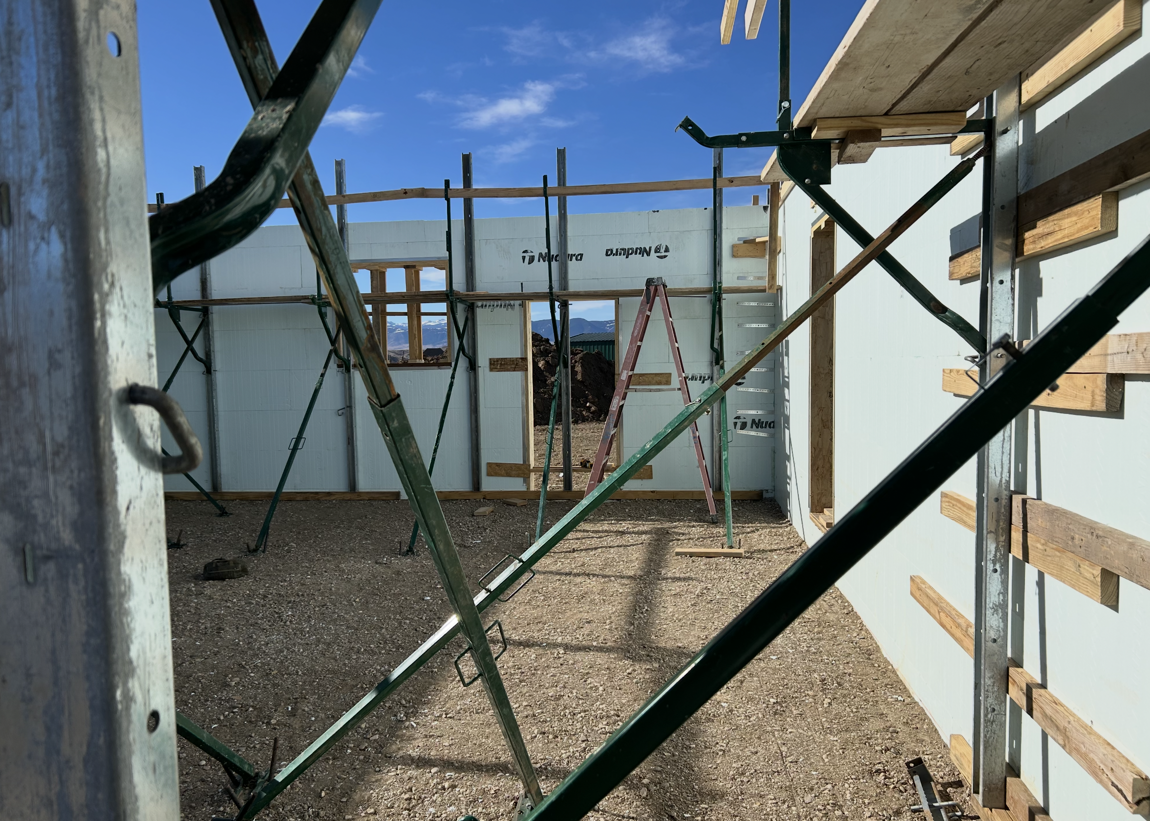 Construction site with framing and scaffolding in progress, clear blue sky in the background.