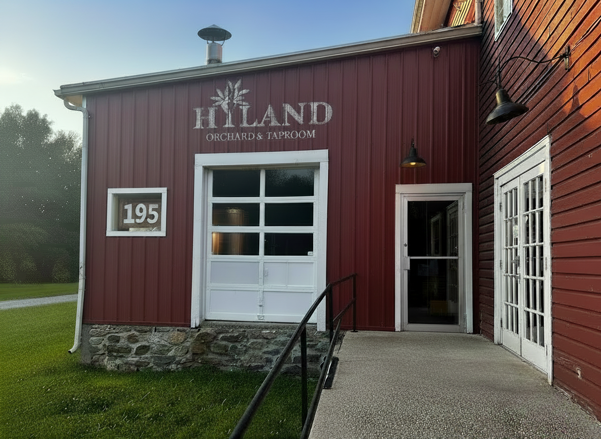 Red building with white trim, displaying the sign 'HILAND ORCHARD & TAPROOM' above the door, with house number 195 on a small window to the left, stone foundation, and outdoor lighting fixtures.