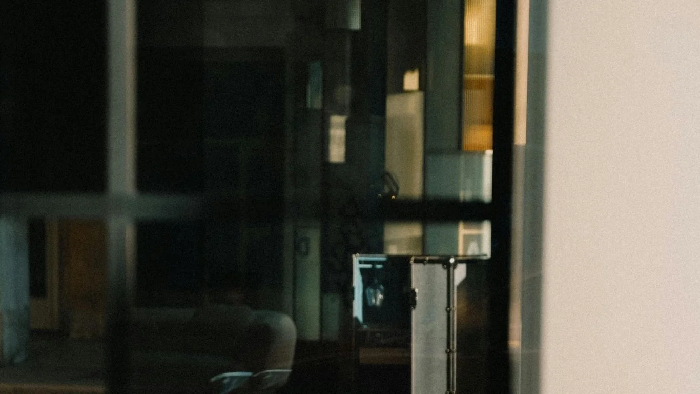 A reflection of a room with furniture and lights seen through a glass window with grid patterns.