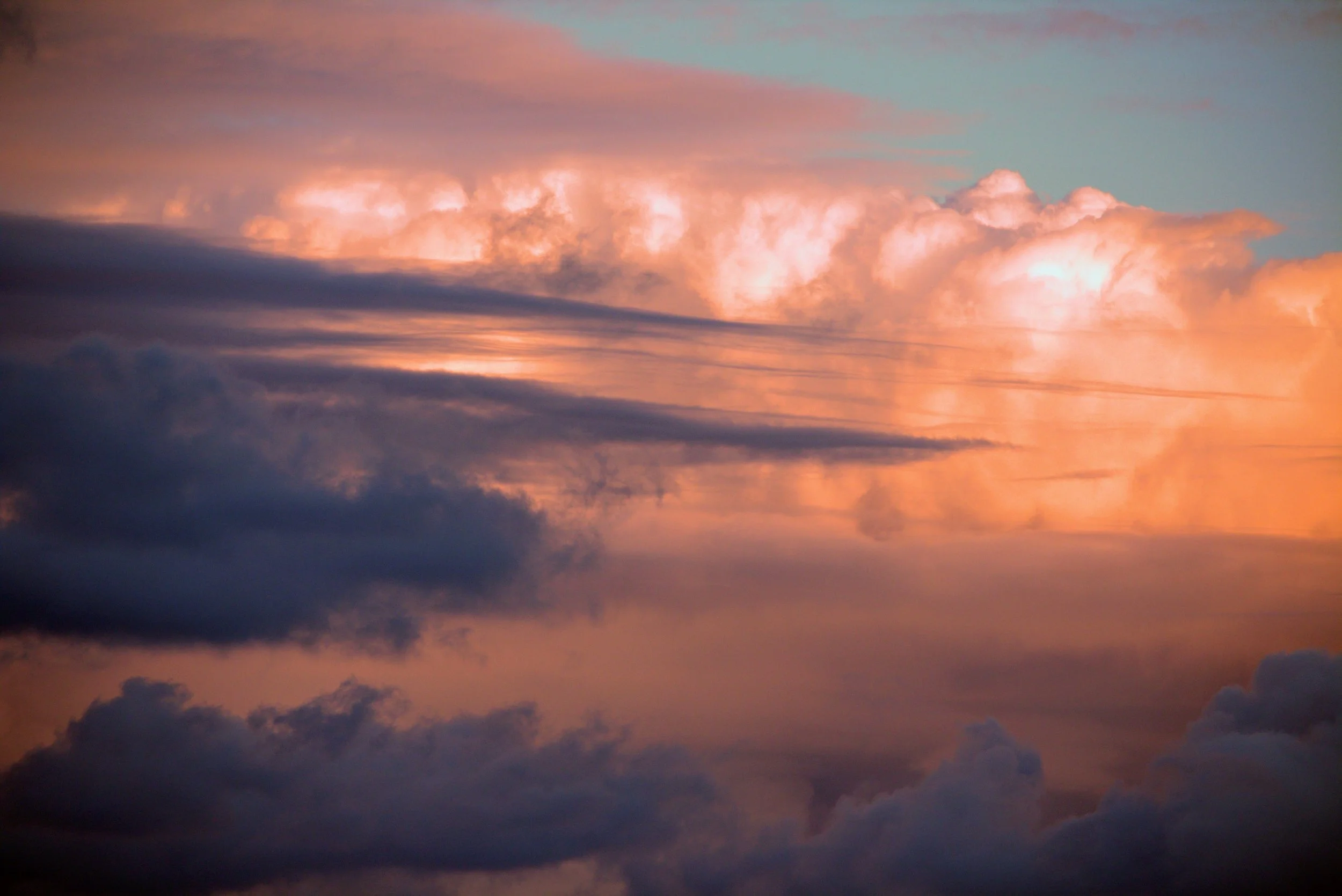 Colorful sky at sunset with pink and orange clouds and dark silhouettes of clouds at the bottom.