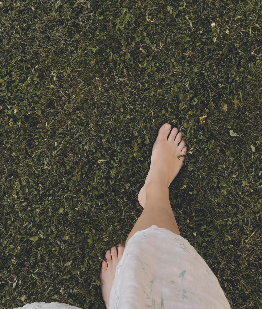 Bare feet standing on green grass, a grounding moment outdoors.