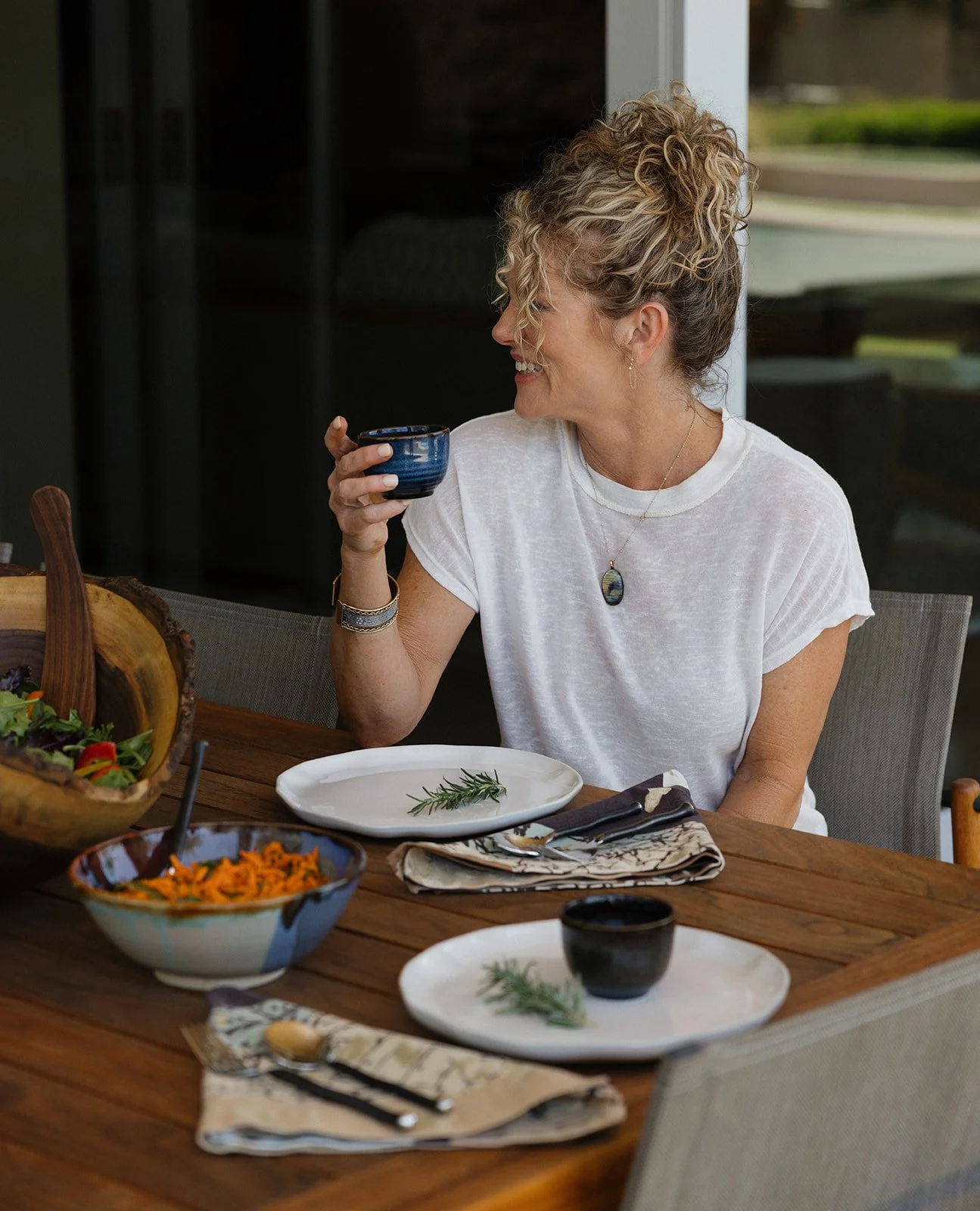 Woman enjoying a nourishing meal at home, seated at a table with fresh salads.