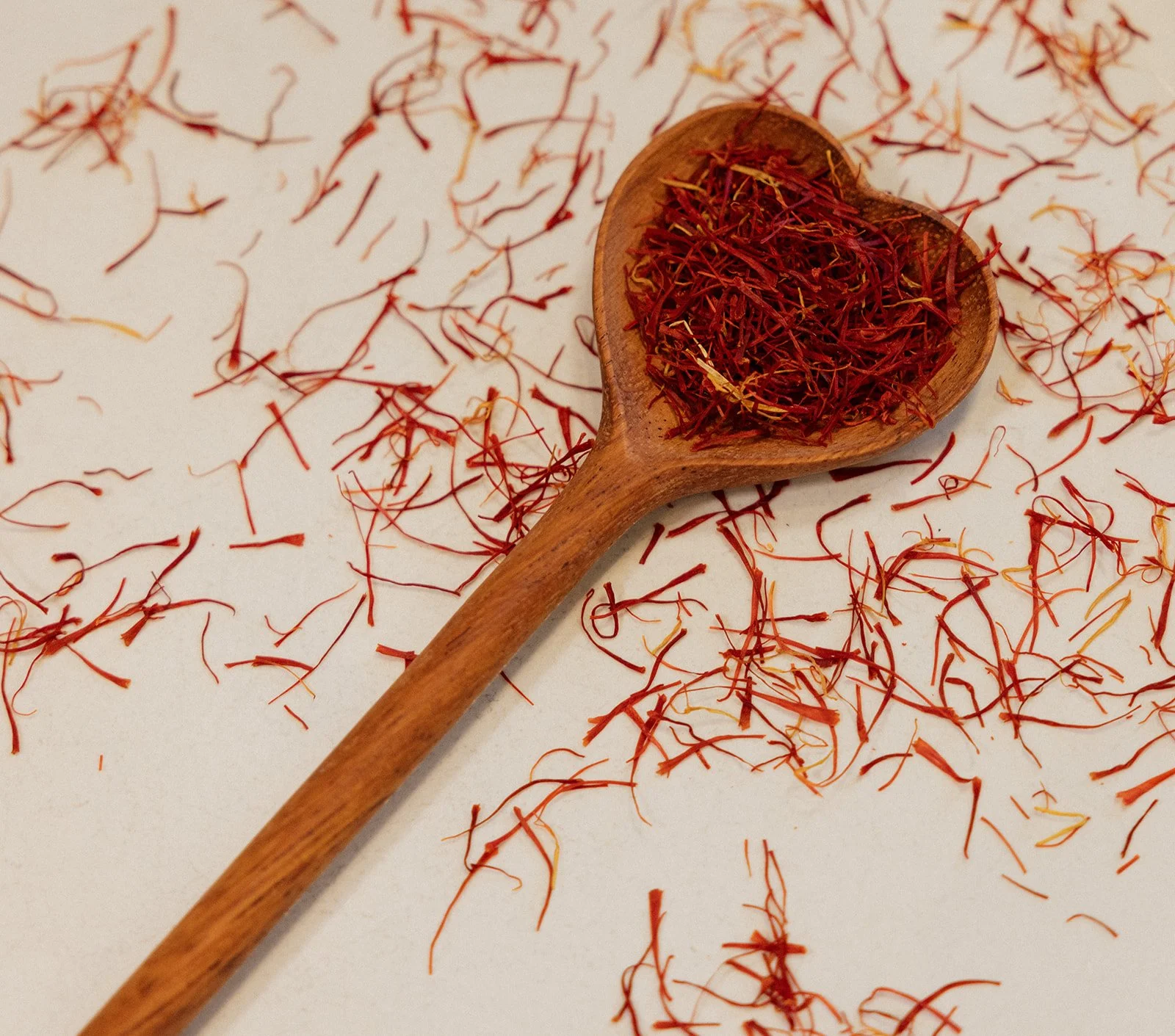 Saffron threads on a wooden spoon, used in traditional Ayurvedic spice preparation.