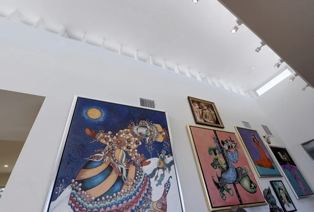 Gallery wall with various colorful paintings in an art museum or gallery.