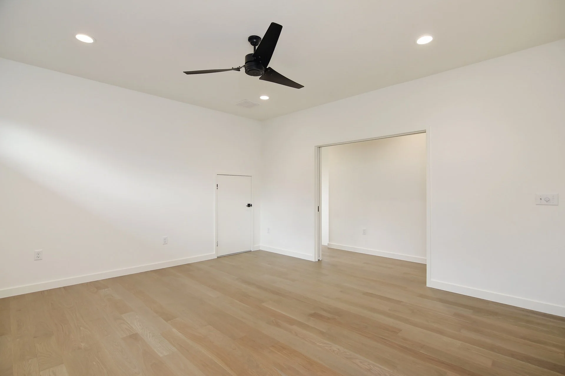 Empty room with white walls, wood flooring, a ceiling fan, and recessed lighting.
