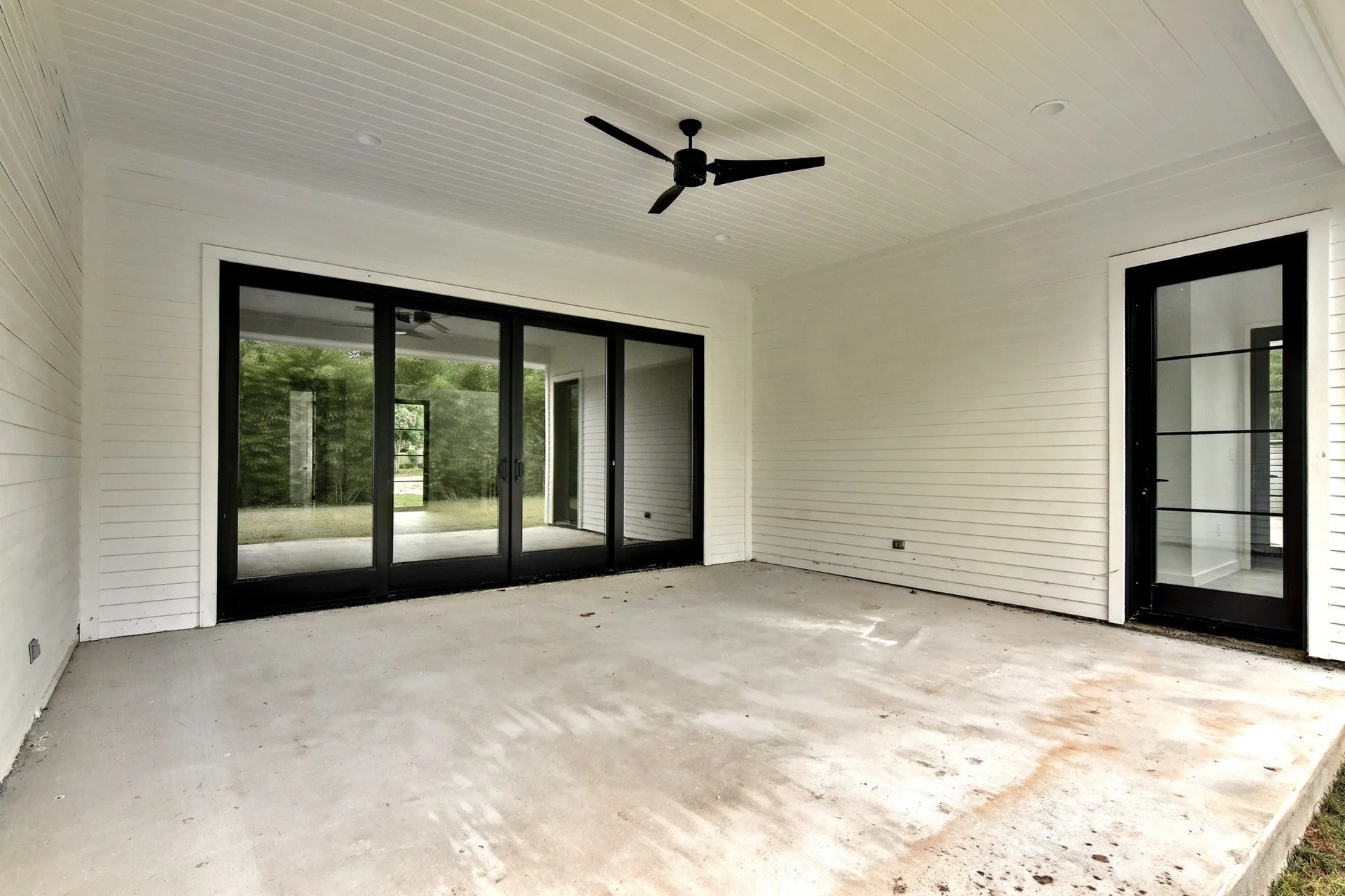 Unfinished screened porch with sliding glass doors and a ceiling fan in a new house.