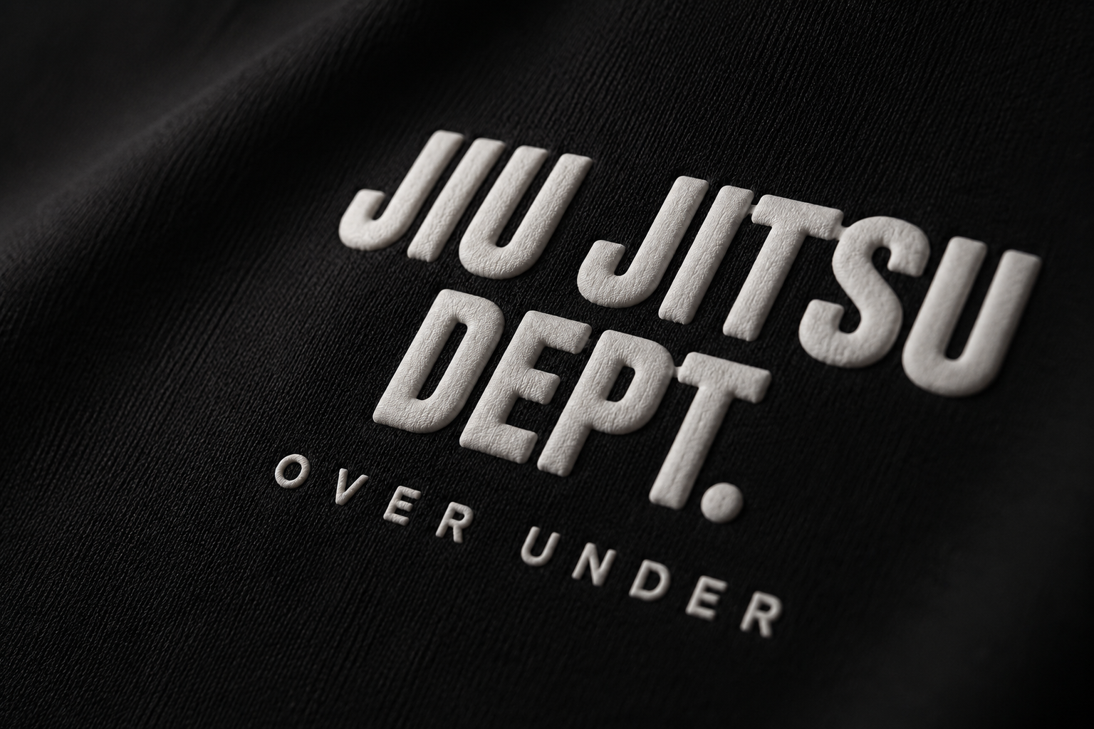 Close-up of a black fabric with white text reading "Jiu Jitsu Dept. Over Under."