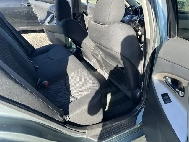 The interior back seat area of a car, showing the passenger seat, part of the front seats, and the driver’s side door.
