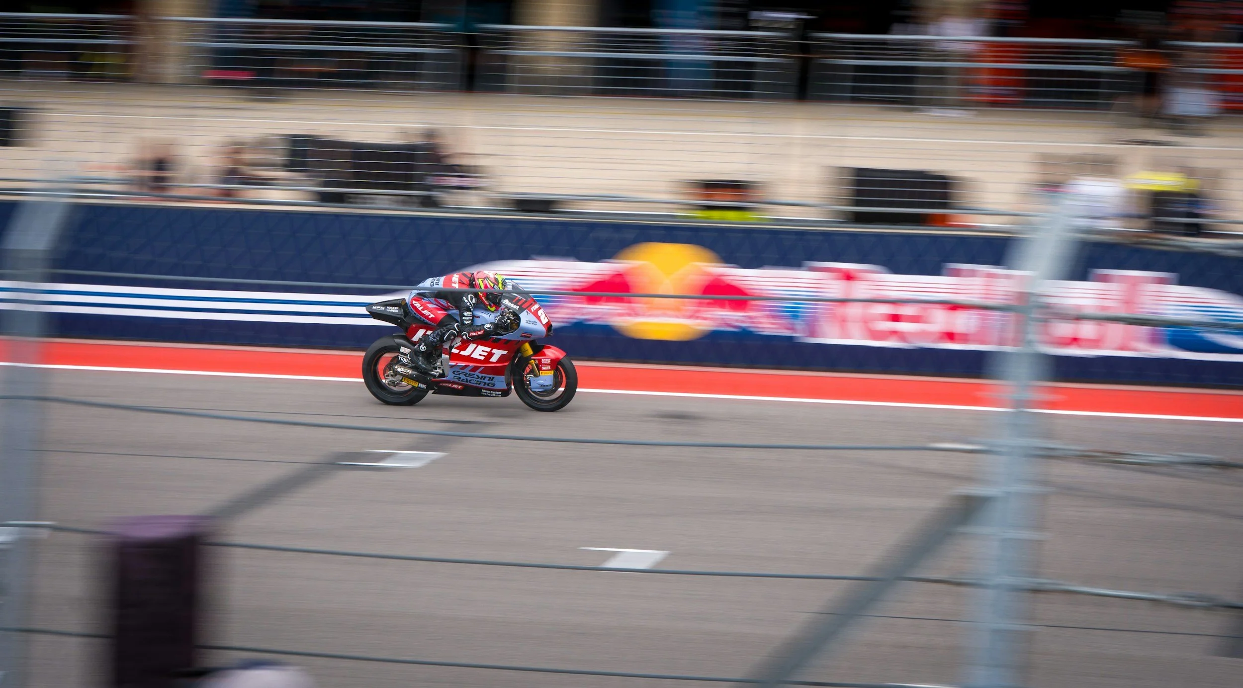 Motorcycle racer speeding on track with tire smoke and blurred background.