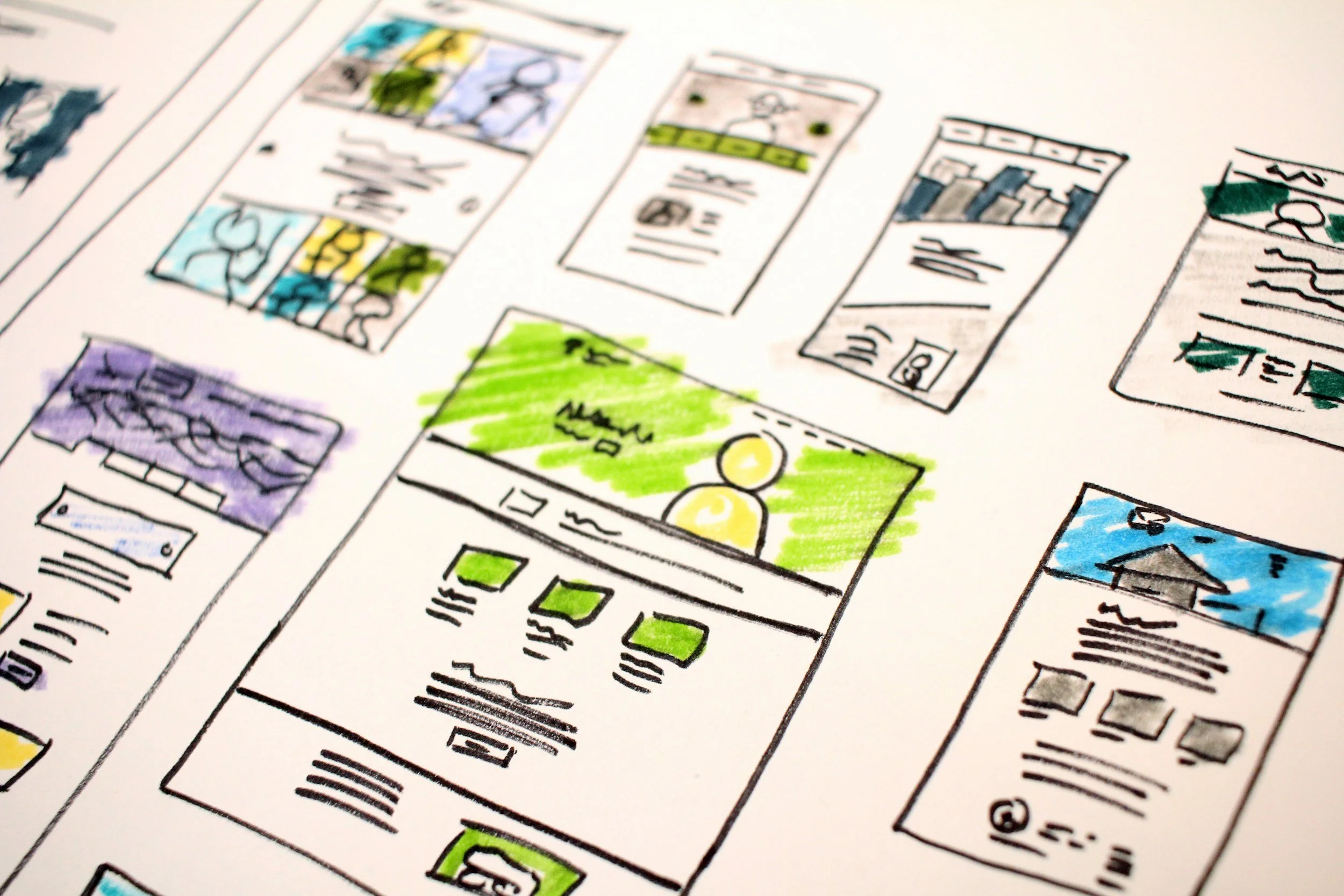Hand-drawn and colored sketches of website or app interfaces on paper.