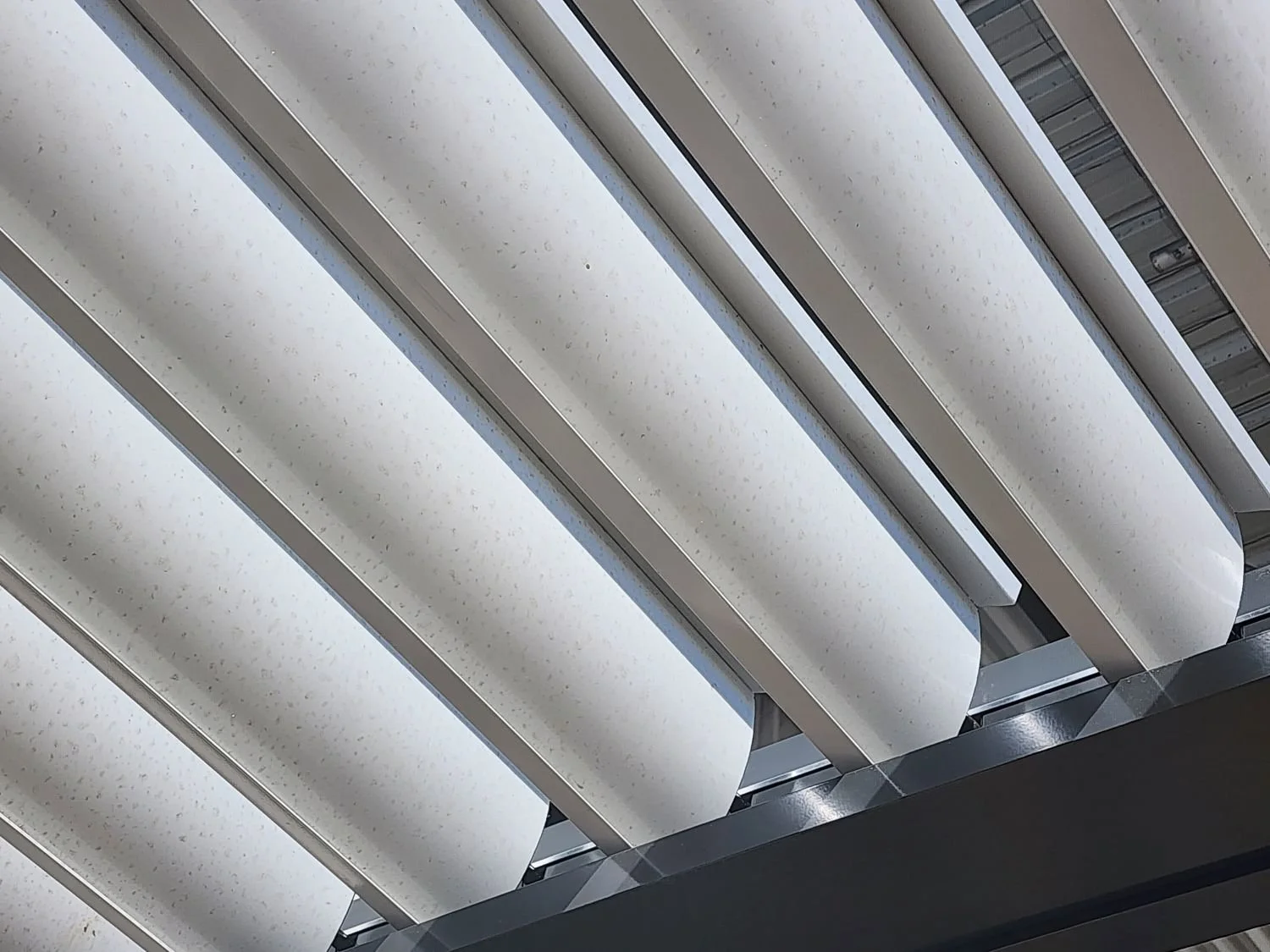 Multiple vertical white panels with rounded edges and speckled surface, part of an architectural or interior structure, possibly a ceiling or facade.
