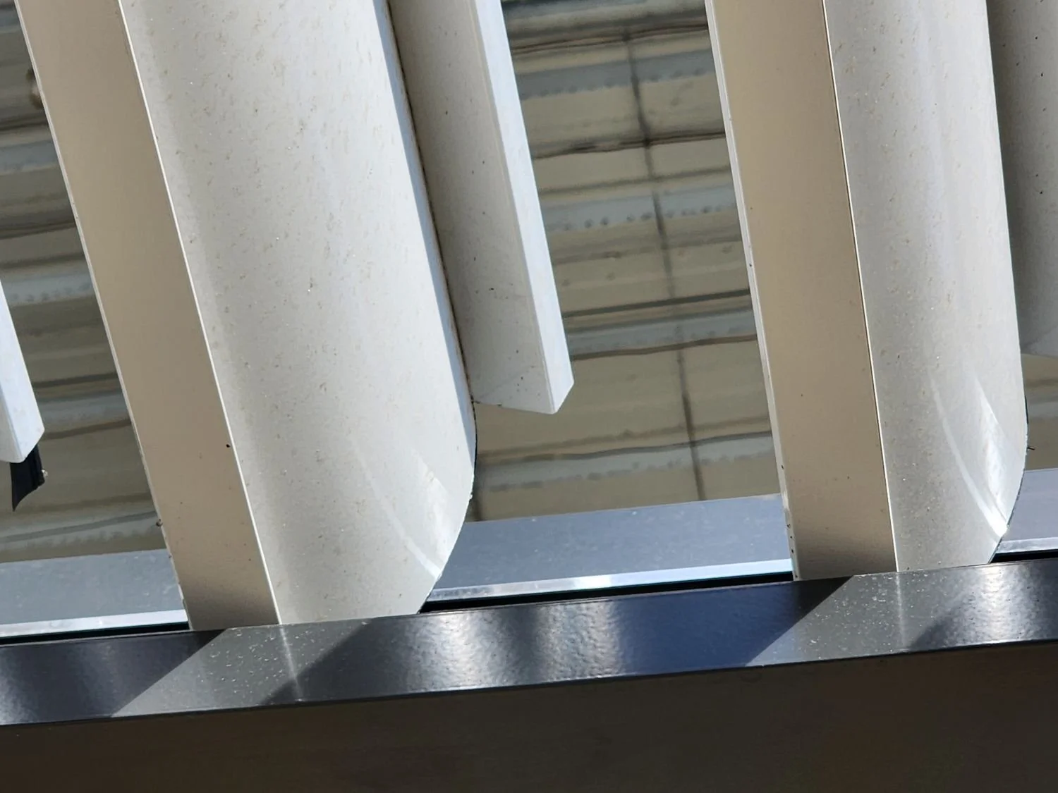 Close-up view of metal shelves or racks, possibly in a commercial or industrial setting, with visible support beams and a reflective metal surface.