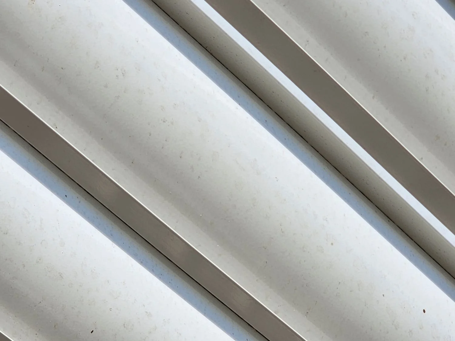 Close-up of a white window blind with dust and dirt on the surface.