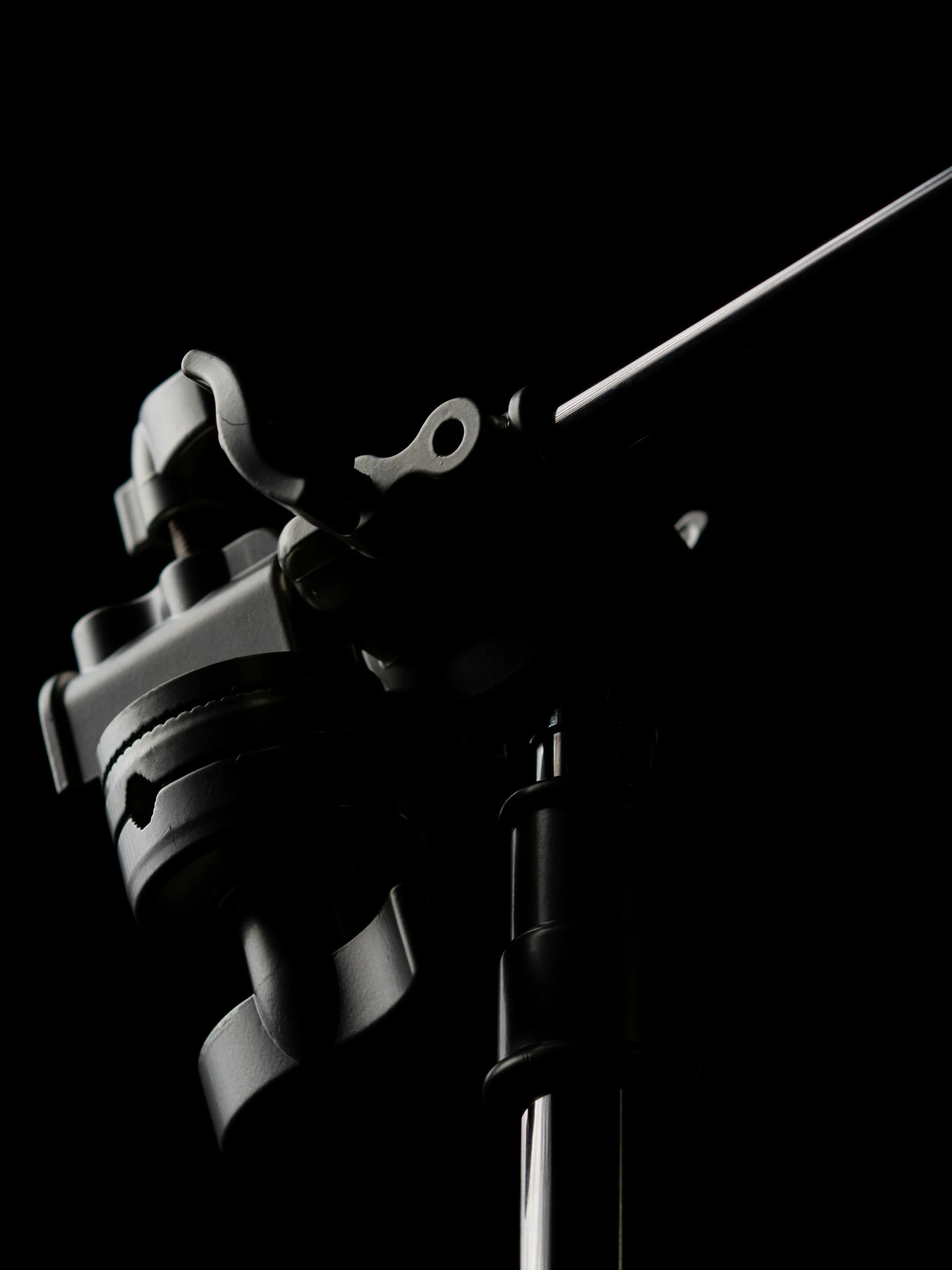 Close-up of a motorcycle front suspension system, showing the fork, shock absorber, and part of the handlebar against a black background.