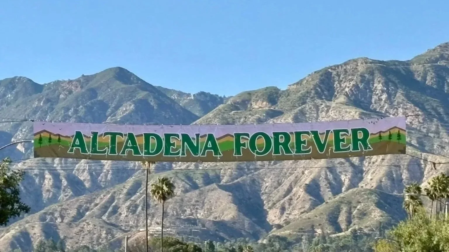 A picture of a banner that says "Altadena Forever" framed against mountains.
