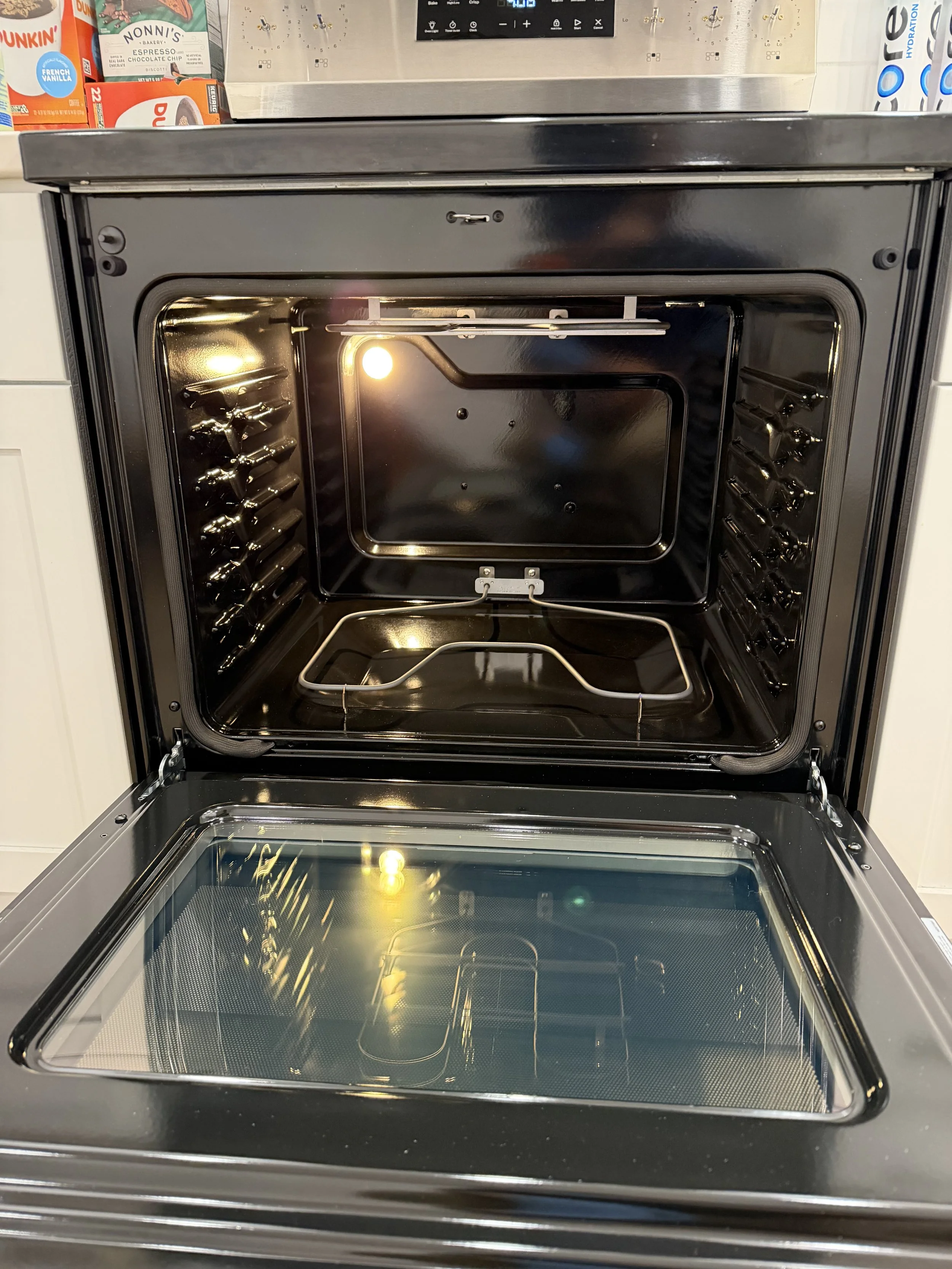 Empty convection oven door open, showing interior with glass window, heating element at the top, and racks on the sides, in a kitchen or appliance store.