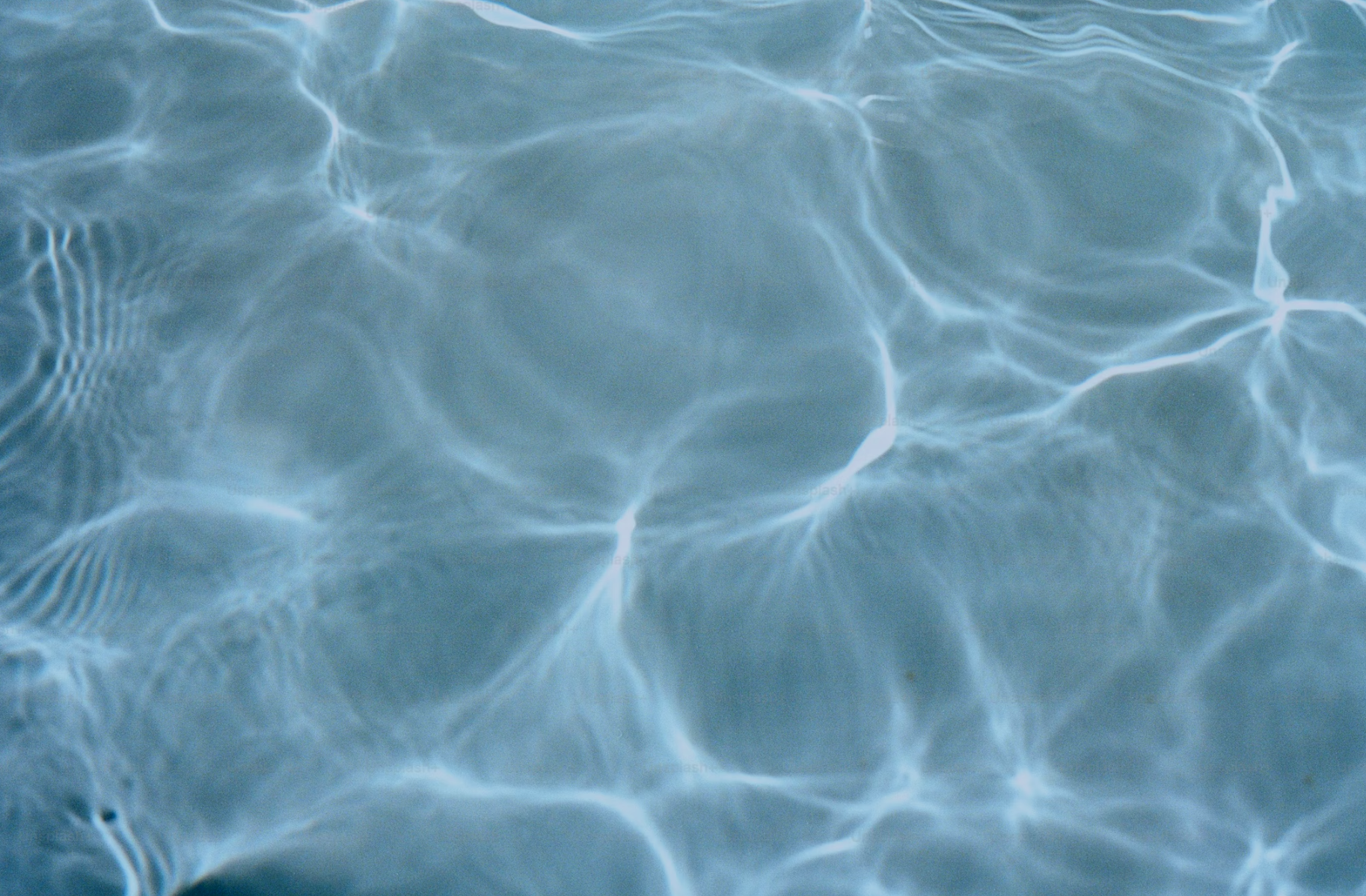Water surface with light refraction creating ripple patterns and reflections.