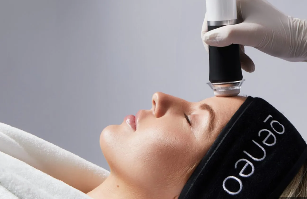 A woman receiving a facial treatment with a handheld device in a spa or medical setting.