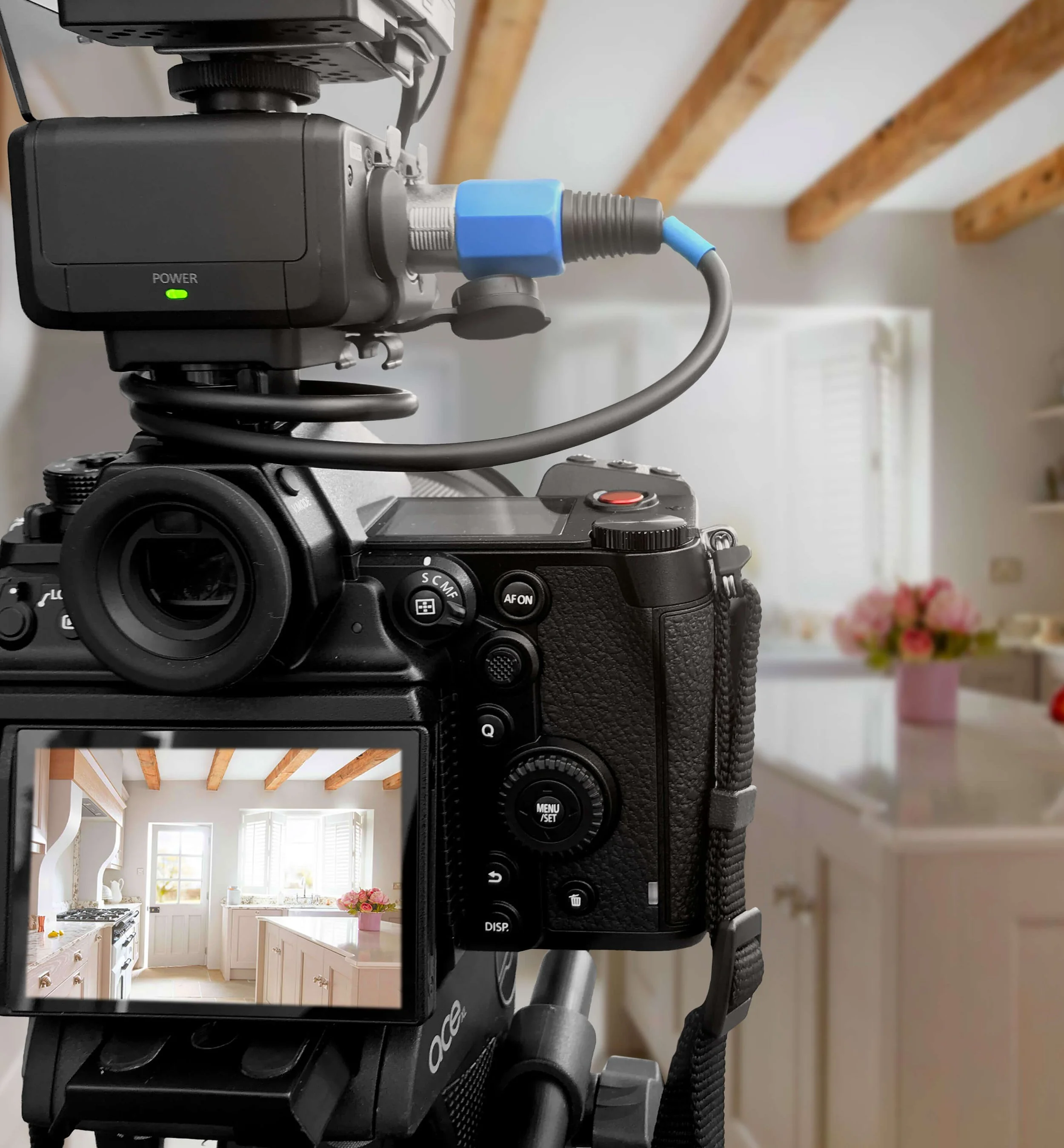 A digital camera capturing a bright, white kitchen with wooden ceiling beams and large windows