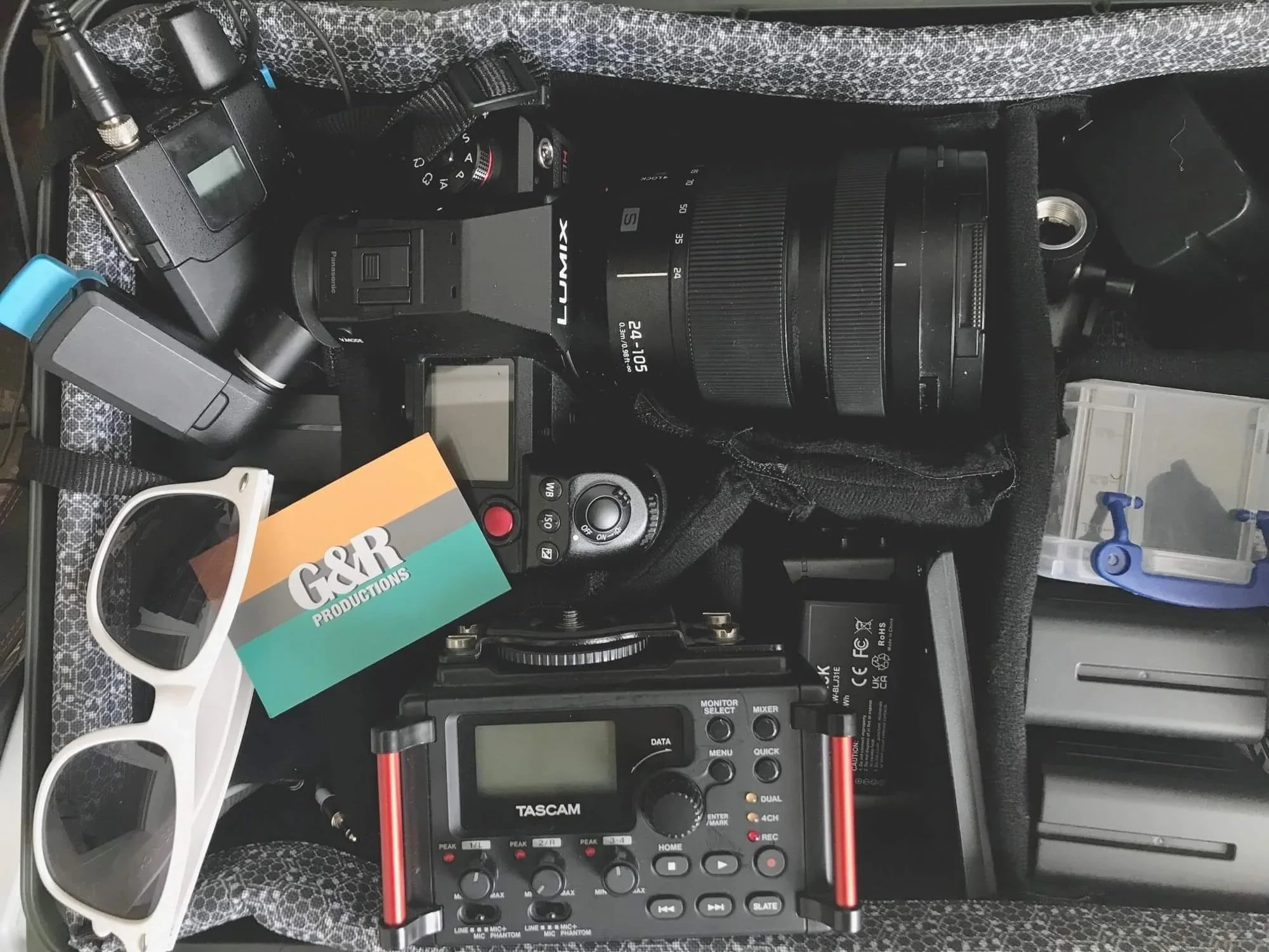 Product videography equipment in a bag, including white sunglasses and a Goose and Racket business card.