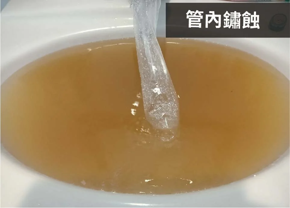 A sink with murky brown water flowing through a pipe. There are Chinese characters on a label indicating the water is rusty.